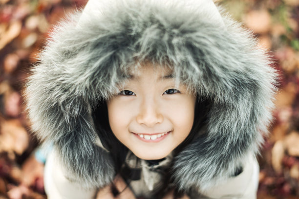 微笑的亚洲小女孩在一个冬天皮帽。图片下载