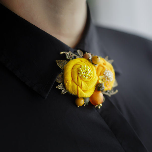胸针由两朵黄花组成，系在一件黑色女式衬衫上图片下载
