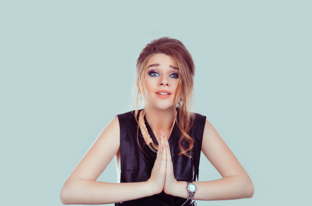 乞讨。特写肖像悲伤的年轻女子祈祷，希望最好的，在她的生活中经历艰难的时刻，孤立在淡绿色的背景墙与复制空间。人类的情感，面部表情素材图片