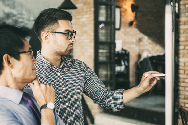 老同事和年轻同事在白板上写字图片下载