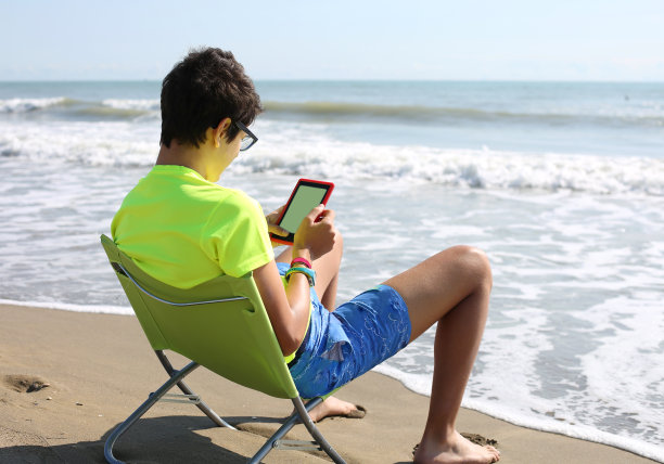 带着电子书和短裤在海滩上的男孩图片下载