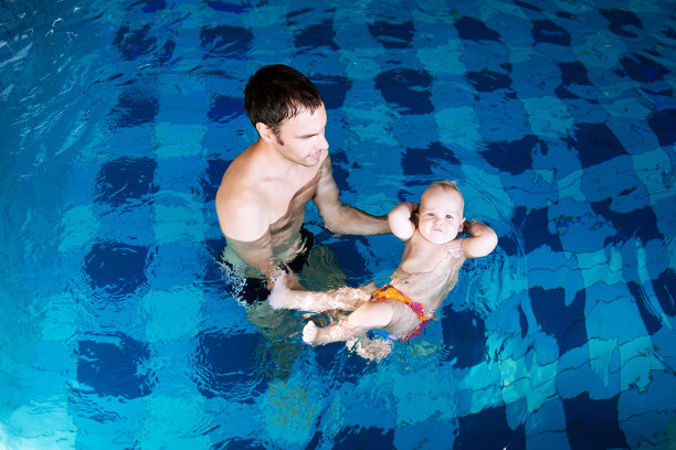 父亲教孩子游泳。孩子在教室里的游泳池里。素材图片