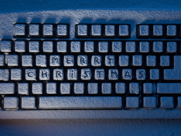 电脑键盘上写着“圣诞快乐”的按钮被雪灯照亮了图片下载
