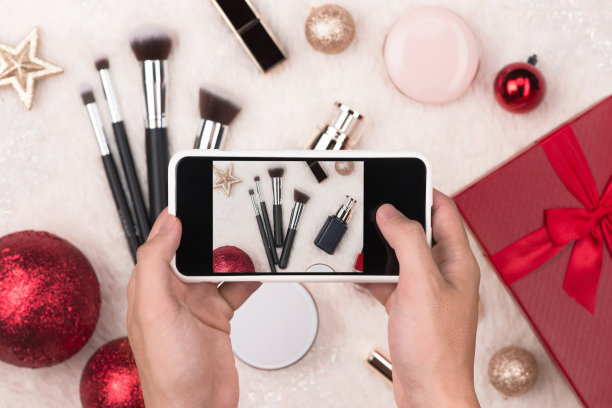手握手机拍摄圣诞化妆化妆品的照片图片下载
