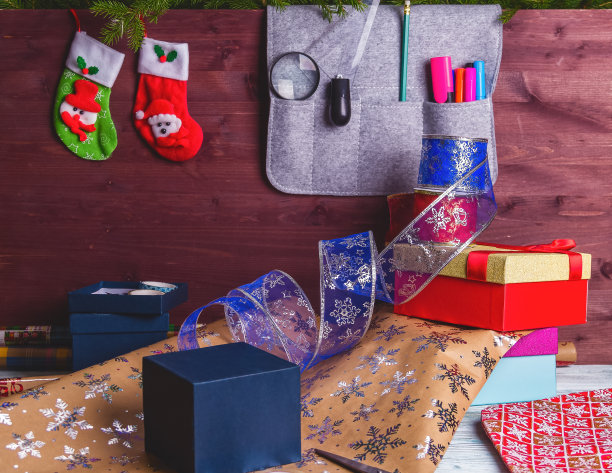 包装圣诞礼盒。新年圣诞包装纸，丝带，蝴蝶结线，剪刀，圣诞树在木制的背景上。冬季新年图片下载