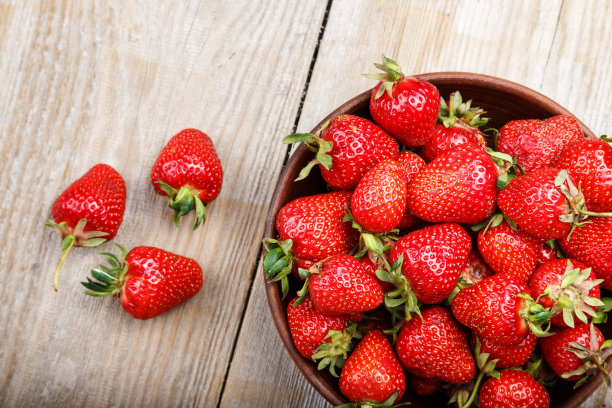 木桌上的黏土盘子里装着新鲜草莓图片下载