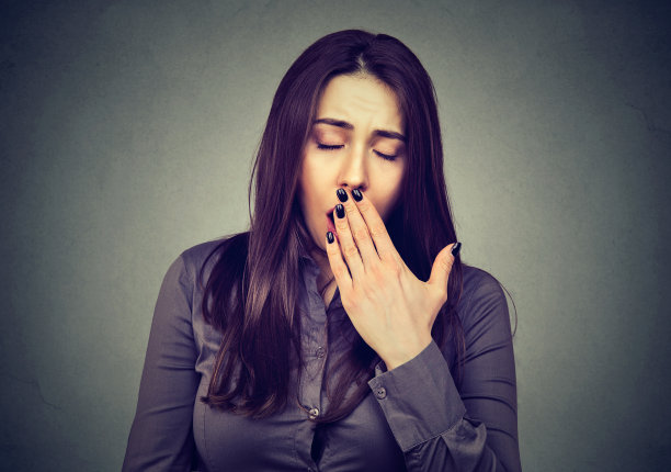 无聊的女人在灰色上打哈欠图片下载