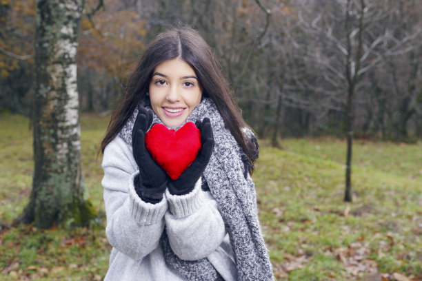 年轻的黑发女人拿着一个心形垫子。图片下载