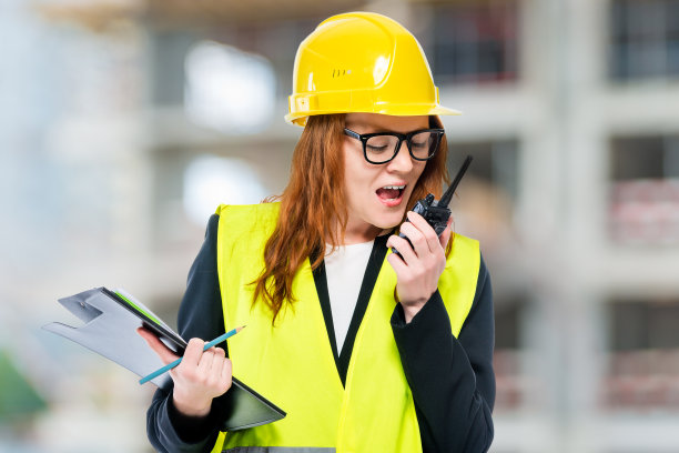 女准将戴头盔，穿马甲，带对讲机在建筑工地图片下载