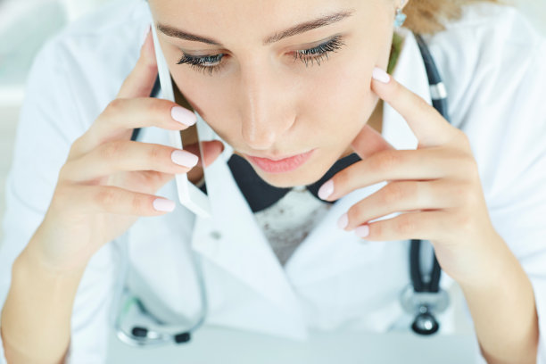 一个年轻的女医生拿着智能手机，与病人交谈的特写肖像。前视图。图片下载