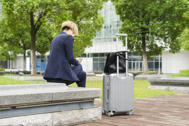 女商人坐在公园长椅上玩智能手机图片下载