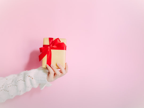 圣诞节和新年的概念与美丽的手女人与冬季布持有礼物，并把它与孤立的粉红色背景的朋友图片下载