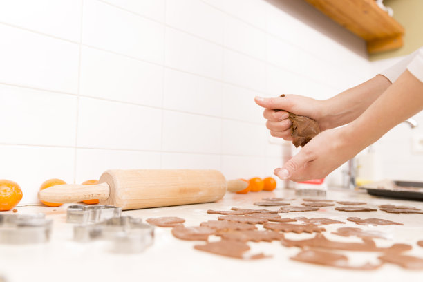 在厨房里为圣诞节做姜饼。女人的手，生面团，姜饼切刀，橘子图片下载