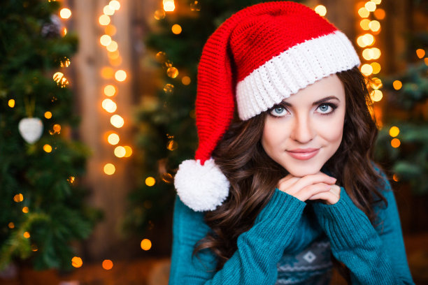 快乐的年轻女子在圣诞树附近的室内。图片下载