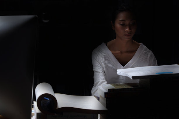 女孩穿着白衬衫读许多课本在桌子上堆放着许多高图片下载