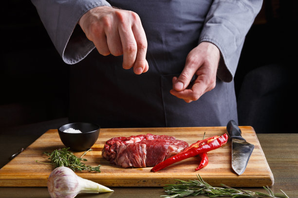 厨师在餐厅厨房的木板上为肋眼牛排调味图片下载