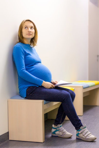 一个孕妇坐在医院的长椅上。图片下载