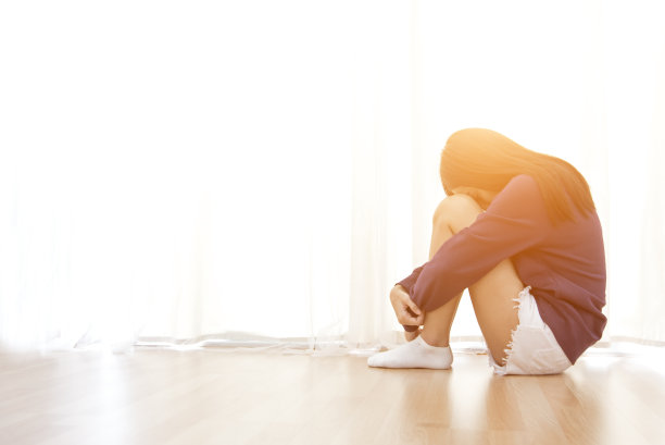 一个悲伤的年轻女子在遭受家庭暴力后坐在自己的房间里捂着脸图片下载