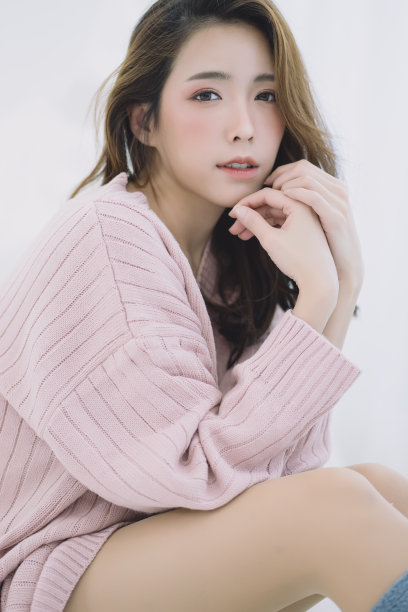 美丽的年轻微笑的女人温暖的毛衣粉红色的寒冷和放松在床上。看相机。模特时尚射击。秋、冬的季节。图片下载