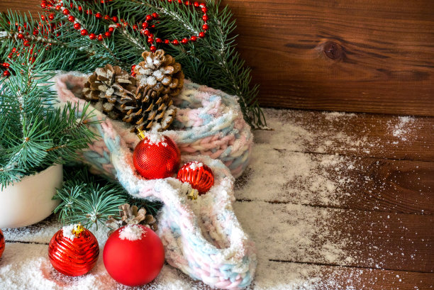 近距离的图片，白色的杯子与冷杉树枝，围巾和新年红色的玩具在雪木的背景图片下载