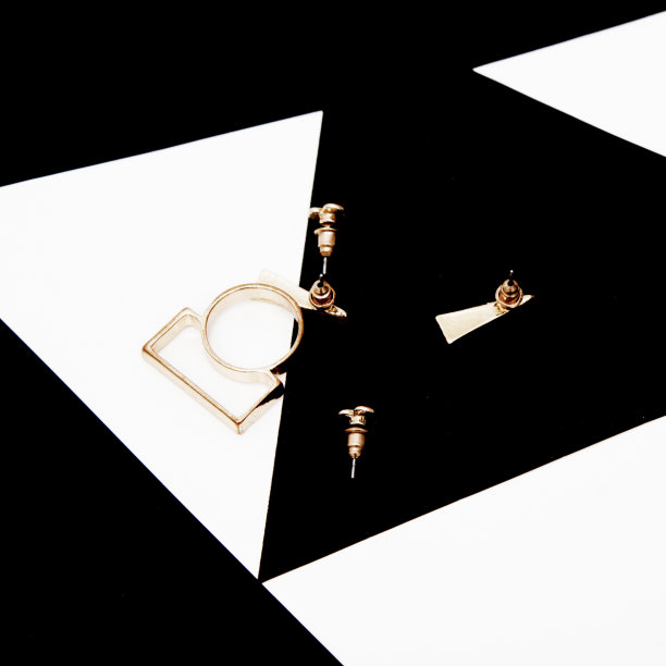 简约的女性时尚配饰。平躺女性休闲风格look。前视图。抽象的黑色背景上的金耳环图片下载