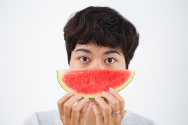 有趣的亚洲女人躲在西瓜片后面图片下载