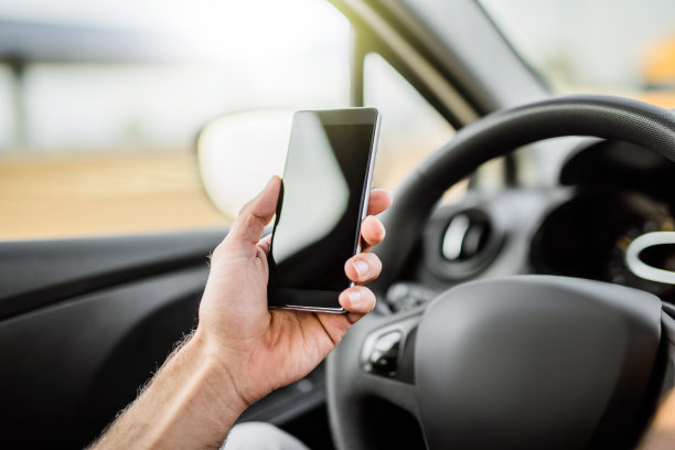 粗心的司机开车时使用手机。素材图片
