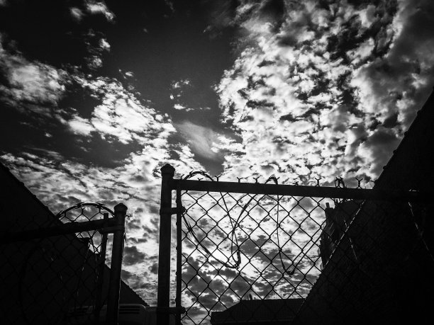 黑色和白色的剪影篱笆和多云的天空图片下载