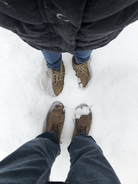 一个男人和一个女人低头看着雪地里的鞋子图片下载