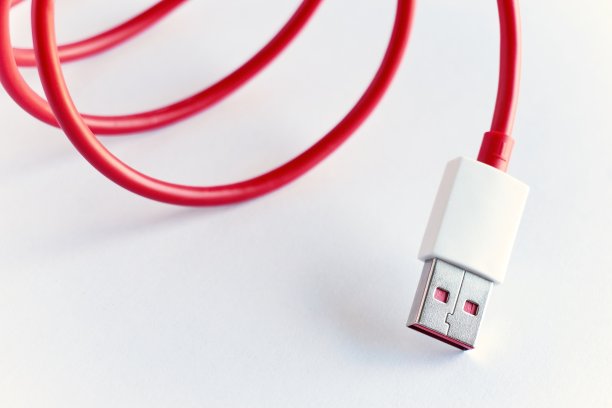 白色背景上的红色卷曲USB电缆的特写图片下载