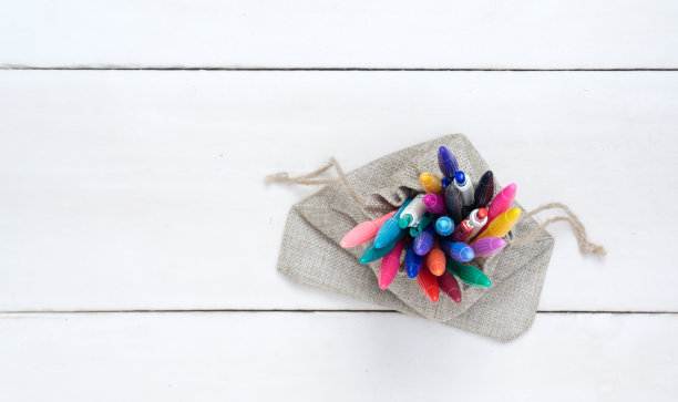 袋子里装着彩色的笔，在白色的木头上图片下载