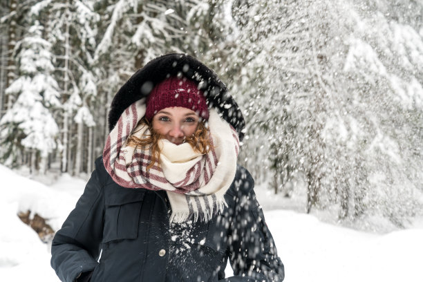 一个年轻的女人在树林里，这时正在下雪图片下载