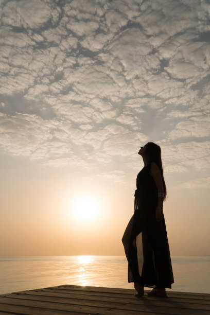 穿着泳衣和斗篷的女孩站在码头上迎接黎明图片下载