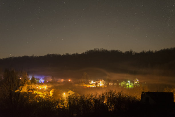 在平安夜的小村庄里，由五彩缤纷的公共照明和装饰性的闪电与星星组成的夜空，向西朝向图片下载
