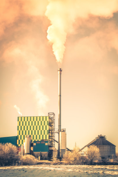 日落时，工业烟囱向多云的天空排放蒸汽和烟雾图片下载