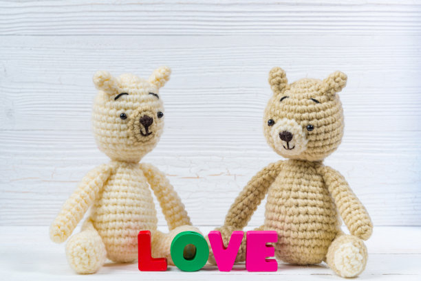 甜蜜的夫妇泰迪熊娃娃在爱的文字和红色编织心在白色木制背景和复制空间添加文字和图片，爱和情人节的概念。图片下载