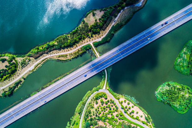 有风的路穿过森林和湖泊，通向日出素材图片