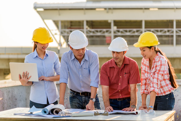 傍晚，多民族的工程师在建筑工地顶部的露台上开会图片下载