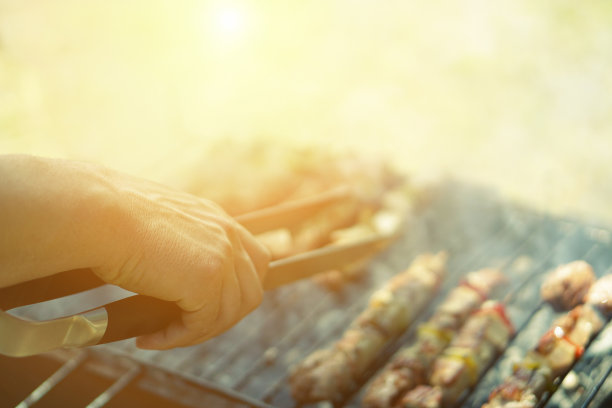 年轻男子烹饪肉烧烤-厨师把一些肉串在烧烤公园户外-概念户外吃在夏季时间-柔软的焦点在顶级手-复古的过滤器图片下载