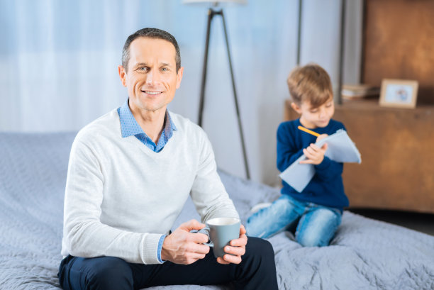 英俊的男人摆着一杯茶在床上图片下载