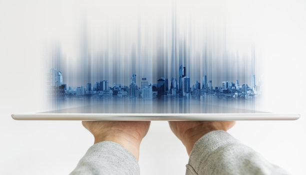 手持数字平板与未来的现代建筑全息图在屏幕上图片下载