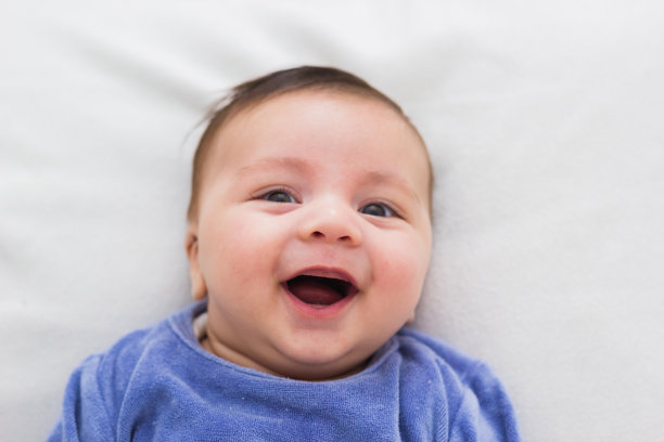 微笑的婴儿躺在他的婴儿床的特写图片下载