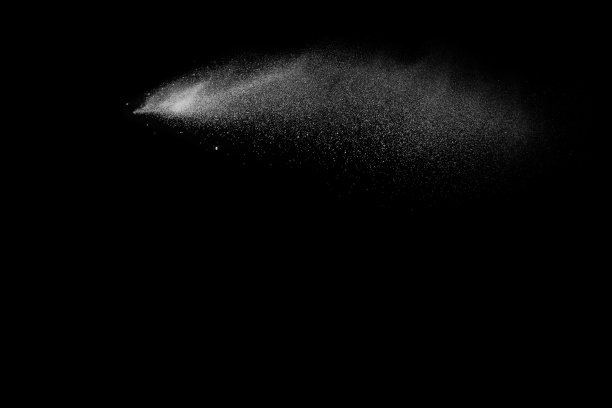 在黑色背景上发射白色粉末飞溅。在黑暗的背景下出现了奇异的白色粉末爆炸云。图片下载