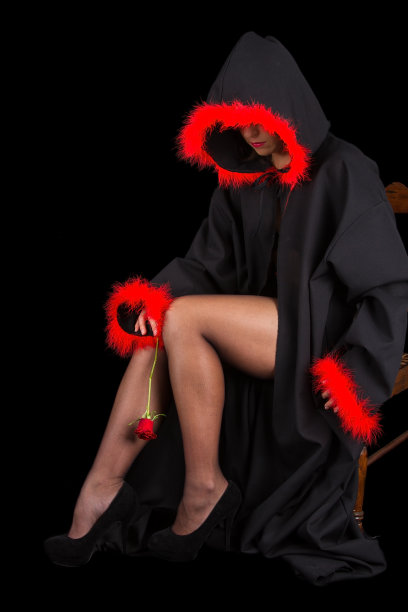 穿着黑色斗篷，带着红色流苏和花的女人坐着图片下载