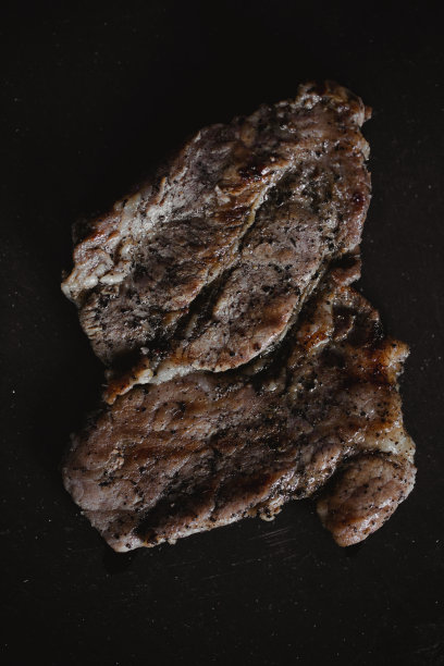 乡村风格的食物照片。烤的肉。深黑背景的石板板上的猪肉牛排。前视图。平躺图片下载