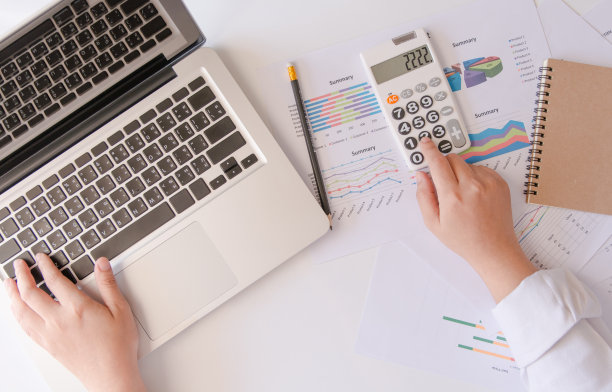 特写俯视图商界女性的手用计算器和笔记本电脑在家里做计数制作素材图片