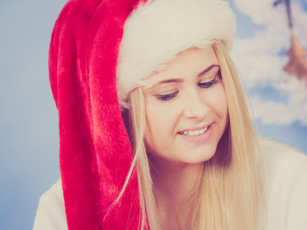 戴着圣诞帽想着圣诞节的快乐女人。图片下载