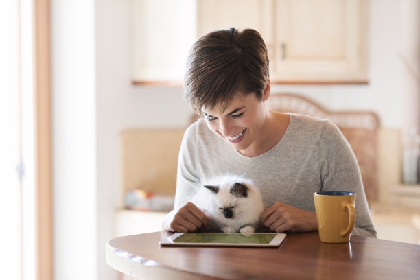 一个女人用着笔记本电脑，抱着她的猫图片下载