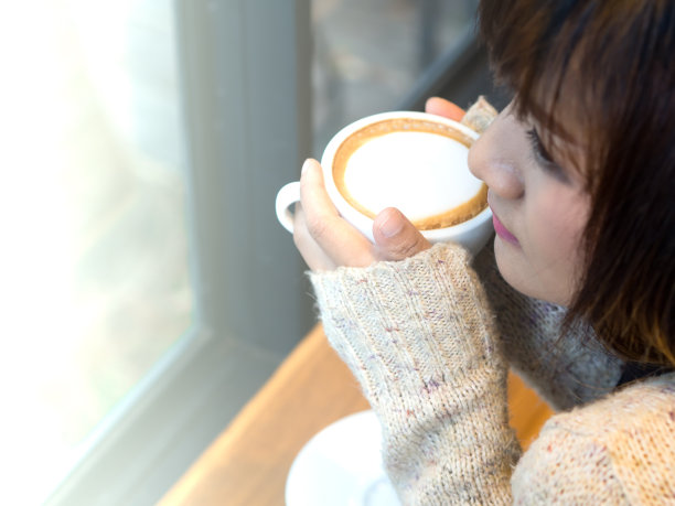 在一个冬天的星期天早上，热咖啡杯在亚洲女人的手与火光图片下载