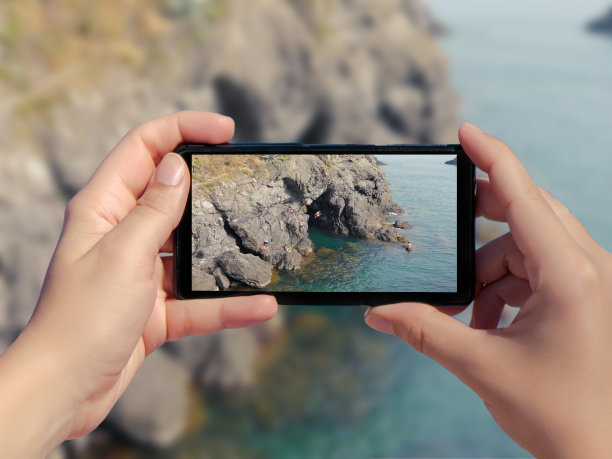 一个女人拍了一张大海和潜水人的旅行照片。一名男子在智能手机的照片上跳入水中图片下载